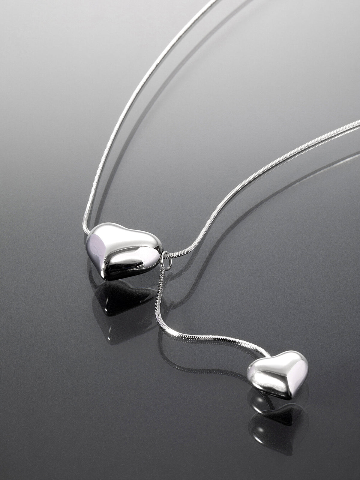 Romantický náhrdelník z leštěné chirurgické oceli s přívěšky ve tvaru srdcí NK1553-0112
