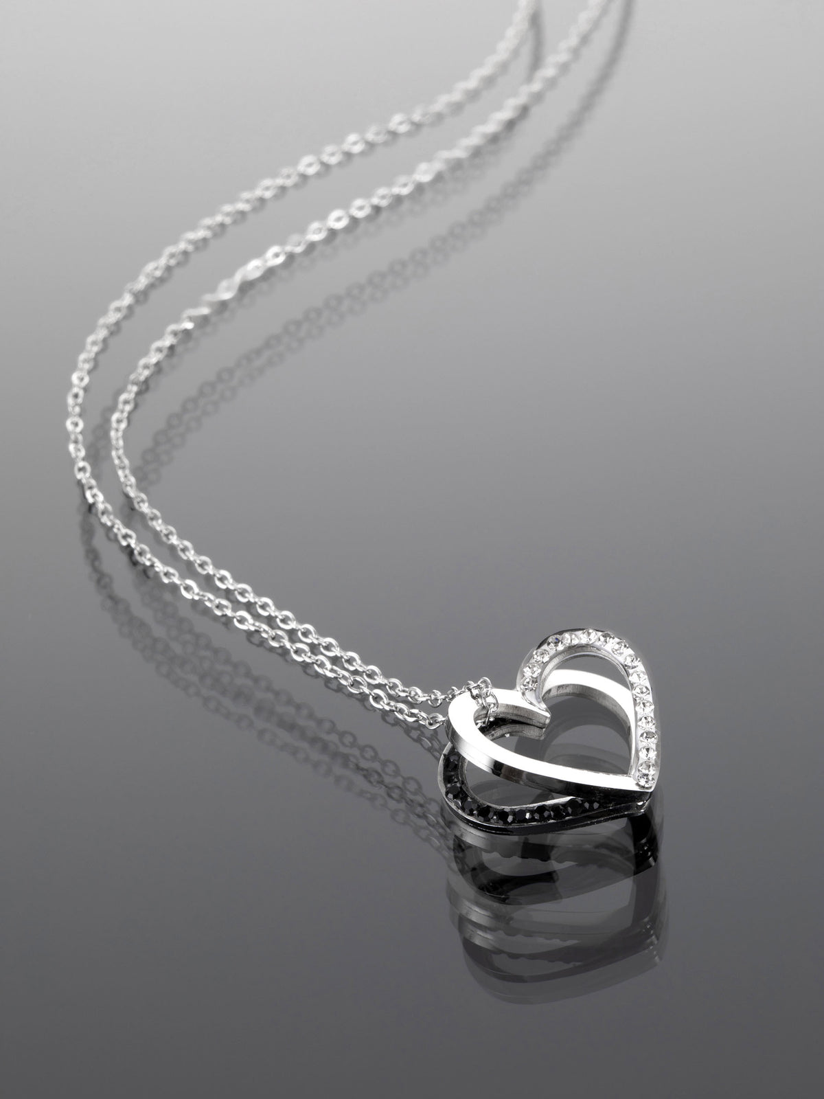 Krásný ocelový náhrdelník ve tvaru dvou prolínajících se srdcí vykládaný čirými krystaly NK0662-0107